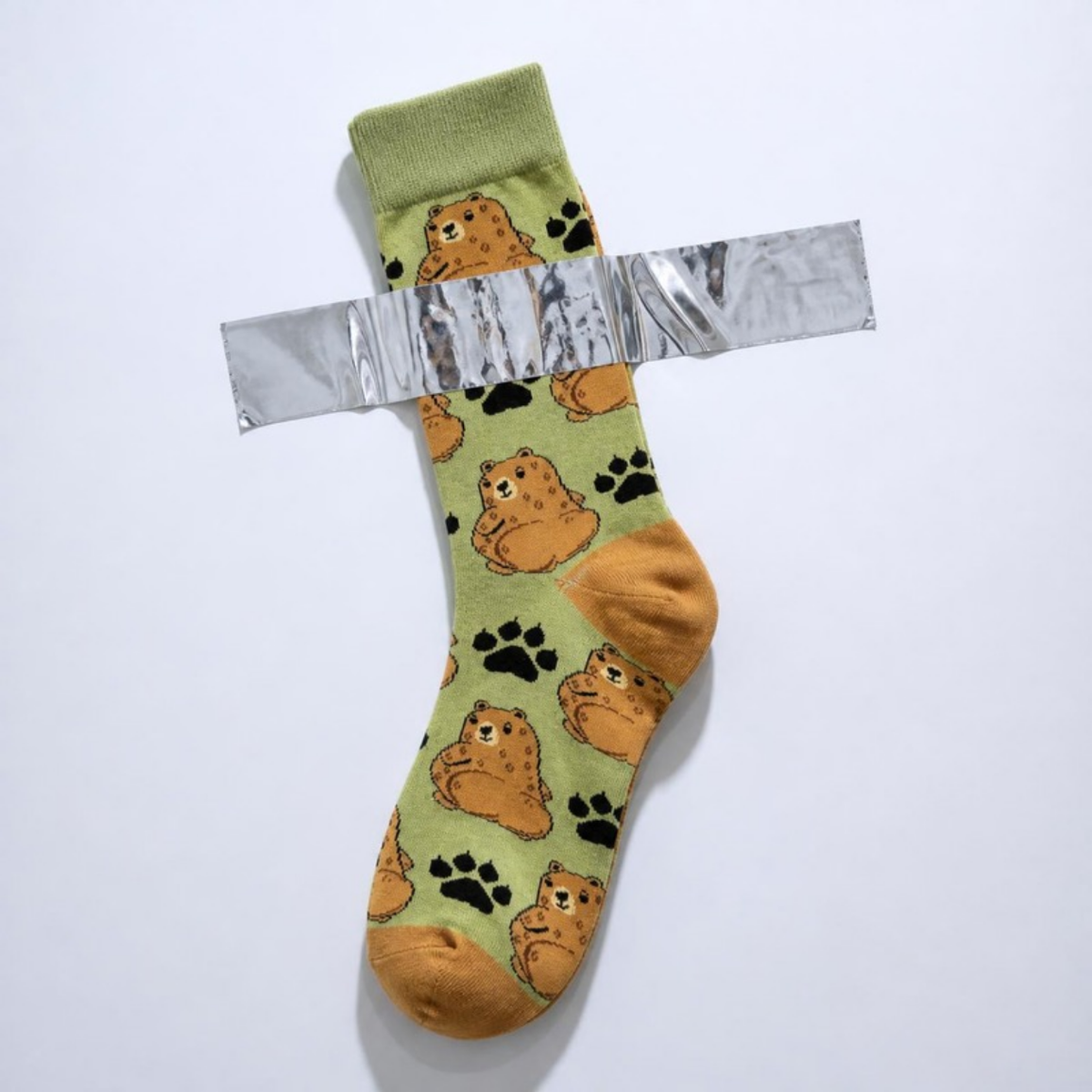 Cuddly Bear Sock taped to a white wall