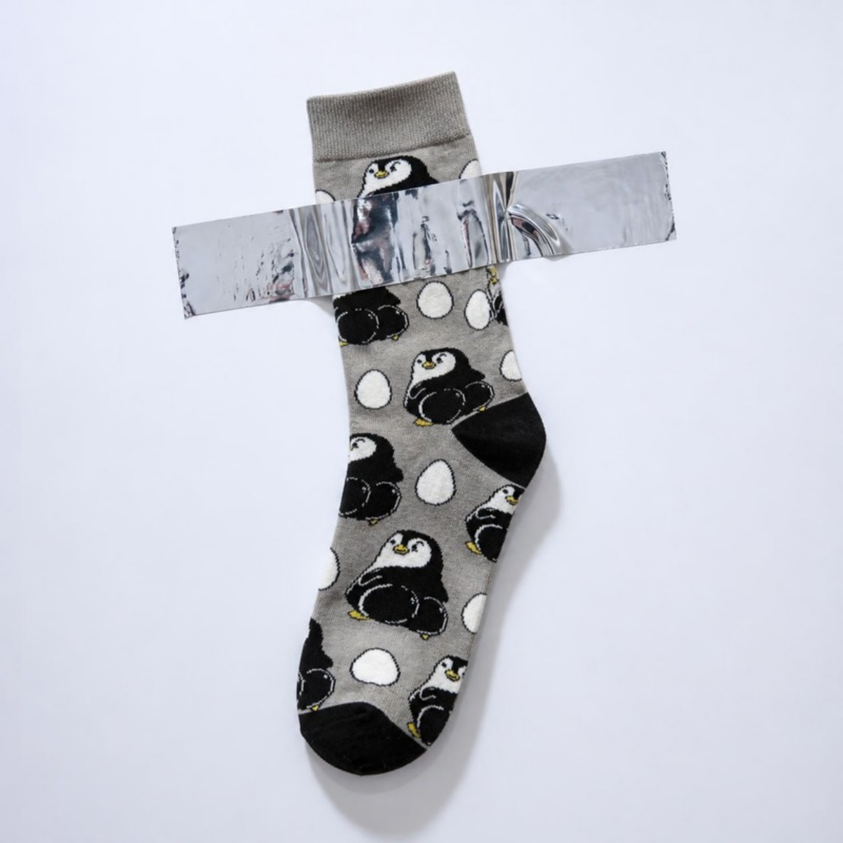 Mischievous Penguin Sock taped to a white wall